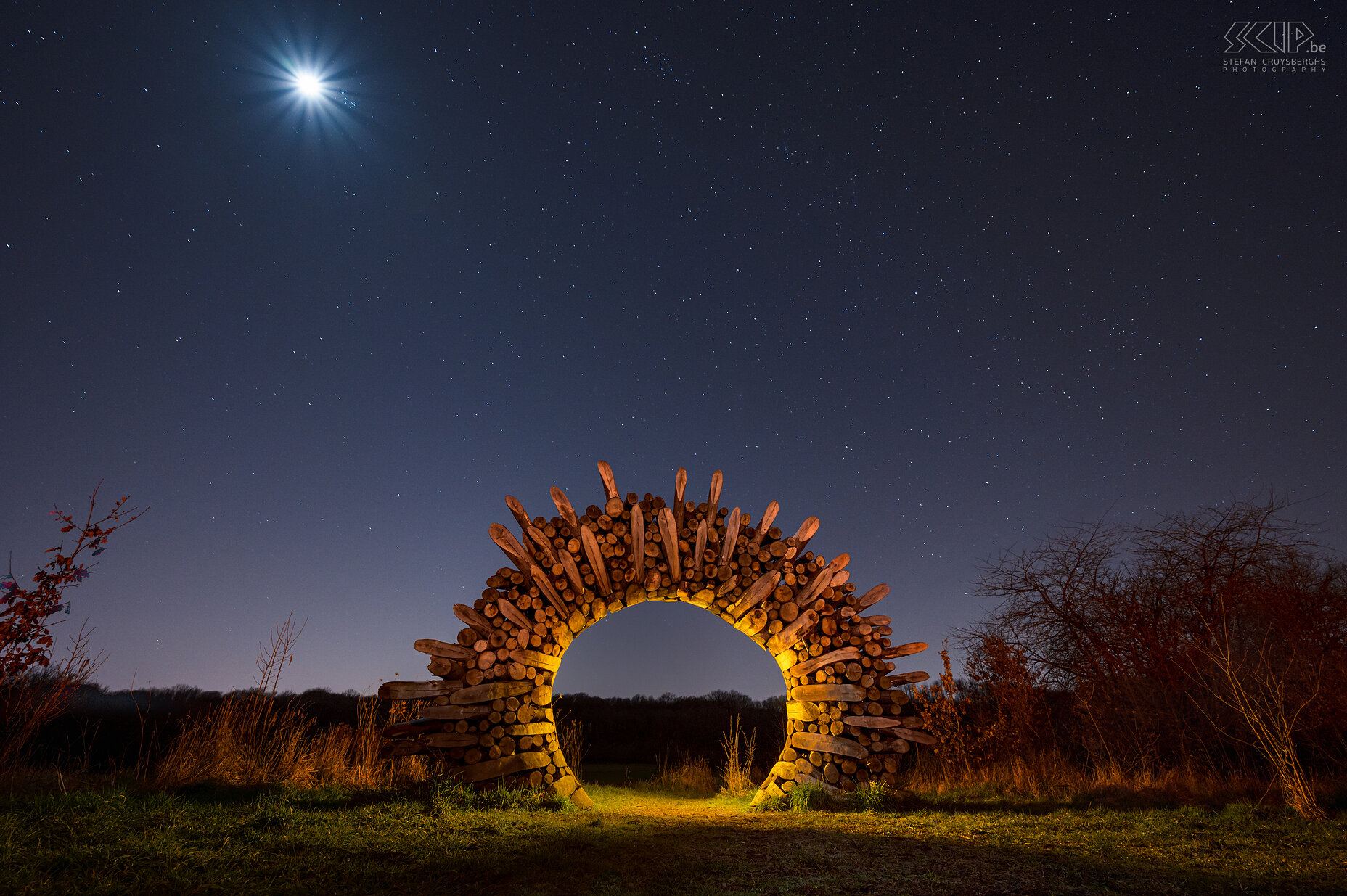 Hageland by night - Volle maan bij de Chartreuzenbospoort in Holsbeek Volle maan en een prachtige sterrenhemel aan de poort aan de rand van het Chartreuzenbos, gelegen in Holsbeek en Lubbeek. De houten poort is een mooi kunstwerk in de vorm van een zon. Met enkele lampen heb ik wat sfeer trachten te brengen. Stefan Cruysberghs